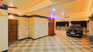 A hotel lobby with a checkered floor, marble walls, a reception desk, and a parked car. - Cozy Apartment w/Living room,WIFI,Kitchen,Laundry & Parking in Velachery,Chennai (Chennai)