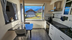 Een keuken met uitzicht op een berg en een houten huis.
