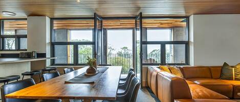 A modern dining area with a wooden table, black chairs, and a leather couch.