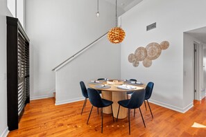 A dining area with a round table, chairs, and a hanging light fixture. - Turf & Tide: Rare Triple Crown Home – Near Beach (Solana Beach)