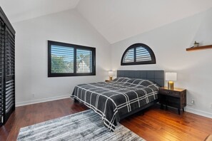Ein Schlafzimmer mit einem Bett, zwei Nachttischen, einem Fenster und einem Oberlicht.