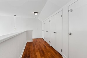 A corridor with white walls, wooden flooring, and a series of white doors. - Turf & Tide: Rare Triple Crown Home – Near Beach (Solana Beach)