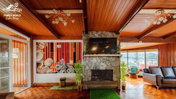 Une chambre de style rustique, avec une cheminée en pierre, un plafond en bois et une grande fenêtre.
