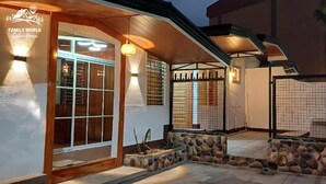 Une maison avec un mur en pierre, une porte en bois et un patio carrelé.