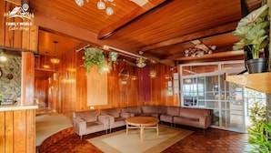 Un salon chaleureux, doté d’un plancher en bois, comprenant un canapé, une table basse et des plantes suspendues.