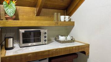 Uma cozinha compacta com forno embutido, máquina de café e uma pequena planta.