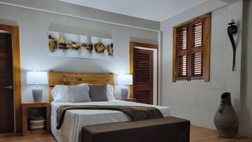 A bedroom with a bed, bedside tables, a bench, a wall-mounted lamp, and a decorative vase.