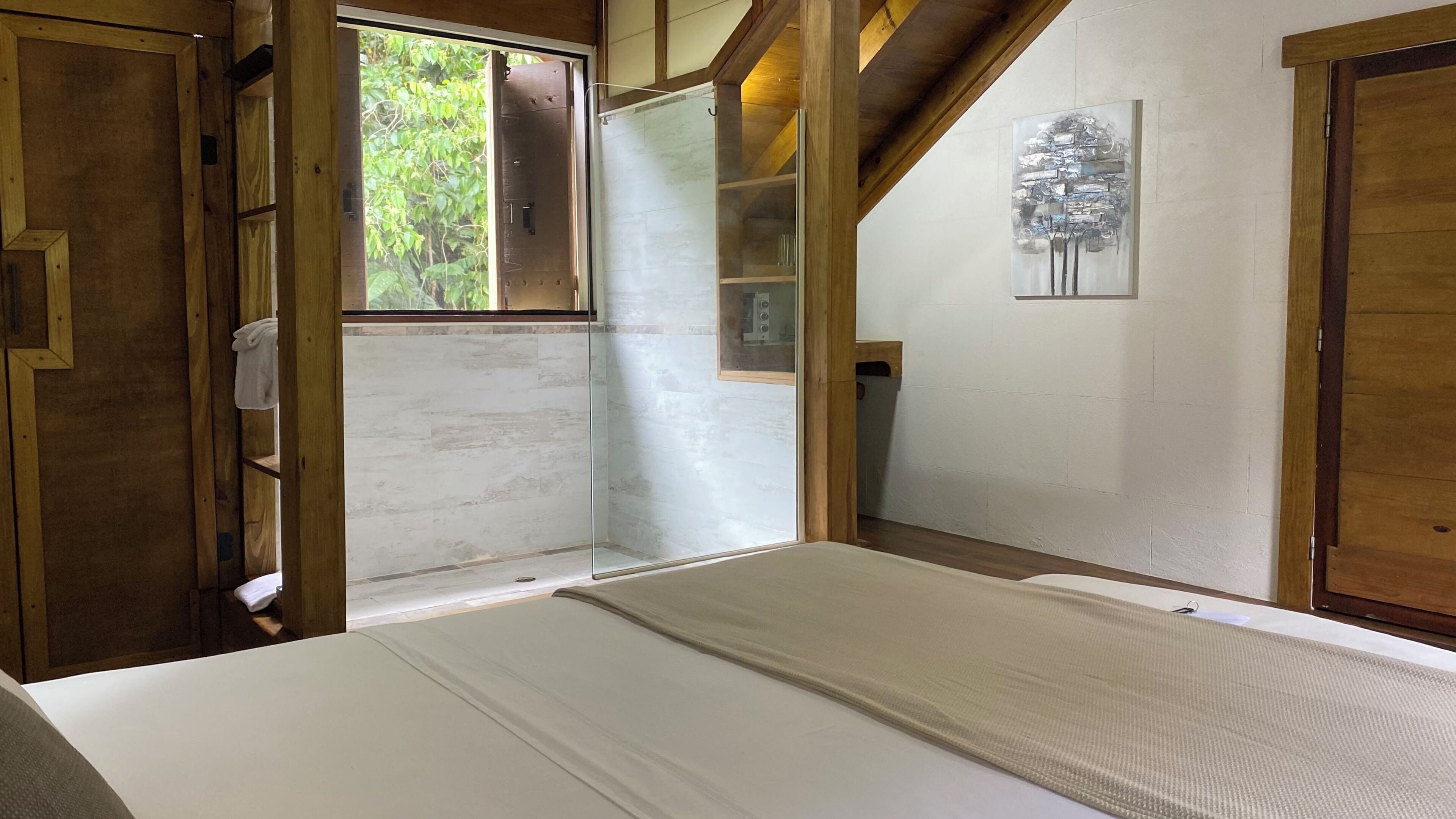 A room with a bed, wooden walls, a window, and a painting.