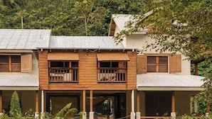 A two-story house with a wooden facade, large windows, and a balcony. - Sabifi River Resort (Castle Bruce)