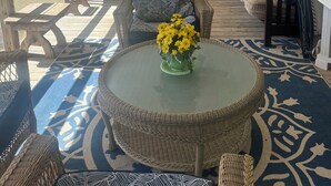 A covered patio with wicker furniture, a round table with a vase of flowers, and a ceiling fan. - Beautiful views on Lake Wateree with large screened in porch, 3 bedroom, 2 bath. (Camden)