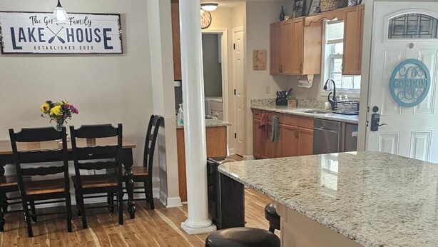 A kitchen with wooden flooring, a granite countertop, and a bar area with stools. - Beautiful views on Lake Wateree with large screened in porch, 3 bedroom, 2 bath. (Camden)
