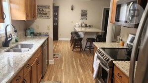 A kitchen with wooden cabinets, a granite countertop, a stainless steel refrigerator, and a microwave. - Beautiful views on Lake Wateree with large screened in porch, 3 bedroom, 2 bath. (Camden)