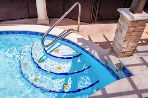 Une piscine dotée d’une échelle en métal, de marches en pierre et d’un bord carrelé.