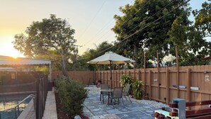 Un patio con piscina, mobiliario exterior y valla de madera.