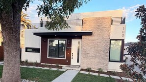 Et moderne hus med to etager, en stenfacade, et stort vindue og en velplejet græsplæne.