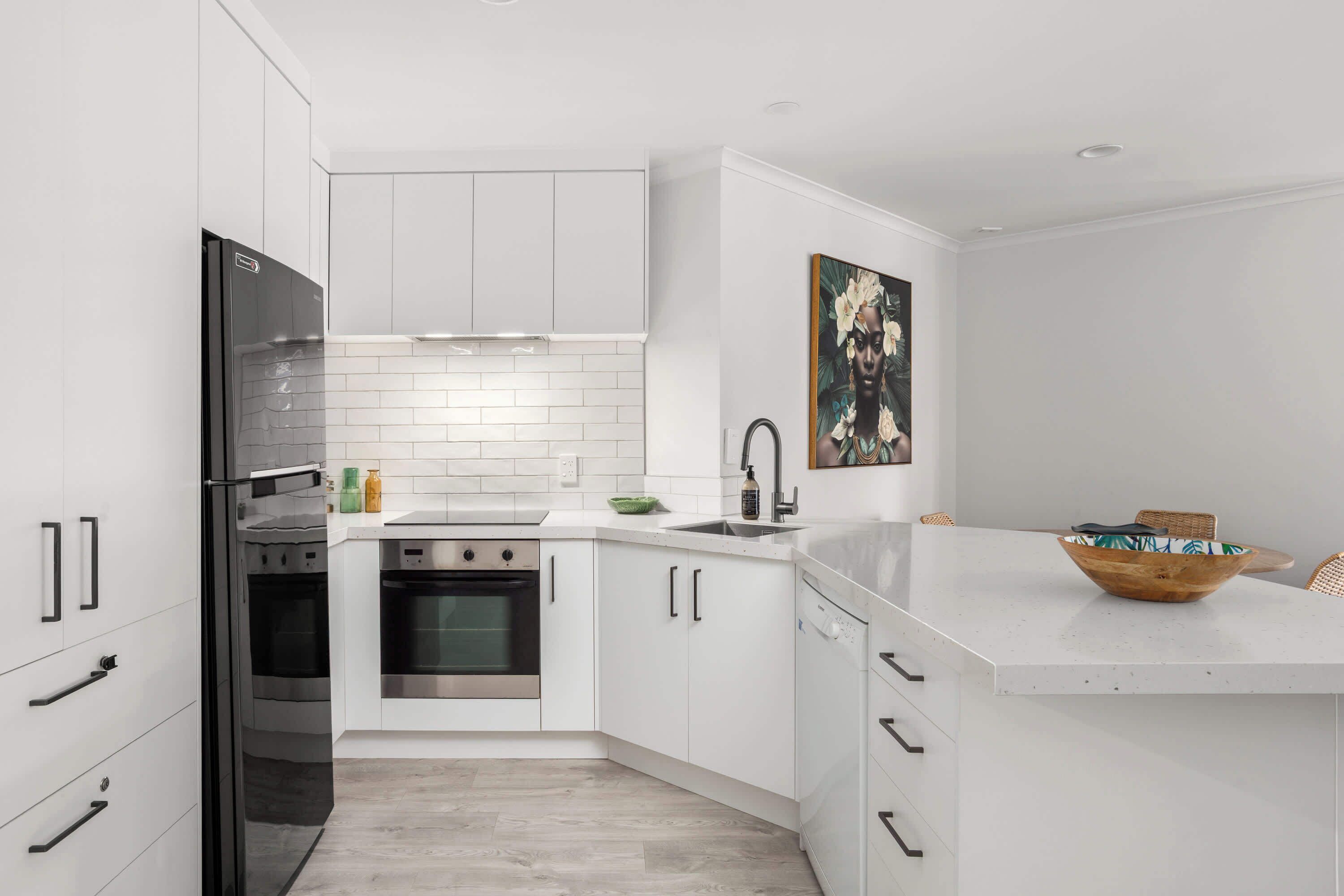 A modern kitchen with white cabinetry, stainless steel appliances, and a white countertop.