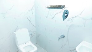 Ein Badezimmer mit Toilette, Bidet und einem kleinen Eimer.