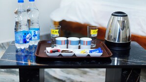 Ein Hotelzimmer mit einem Bett, einem Tablett mit Wasserflaschen, Tassen und einer Kaffeemaschine.
