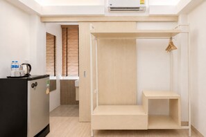 Une chambre d’hôtel compacte comprenant un coin cuisine, un lit pliable et une petite table.