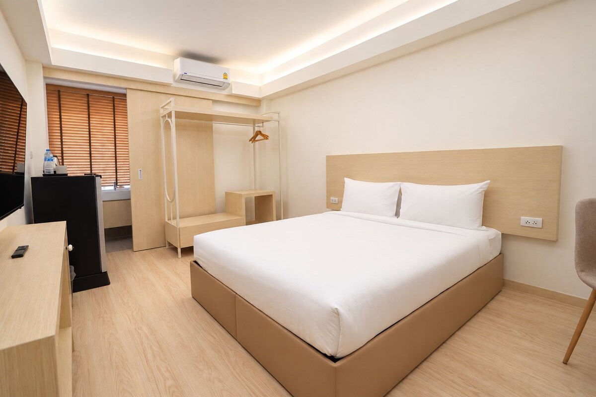 Une chambre d’hôtel comprenant un lit, une table de chevet, une armoire et un bureau avec une chaise.