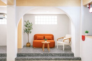 Un intérieur moderne avec un canapé, un fauteuil, une petite table et une plante en pot.