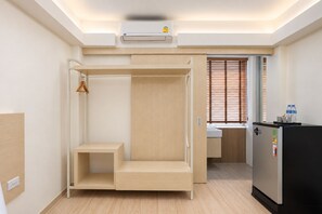 Une chambre moderne et minimaliste, dotée d’un lit superposé, d’une kitchenette et d’une armoire intégrée.