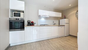 A modern kitchen with white cabinetry, a microwave, oven, coffee maker, and a refrigerator. - Ty Ar Mor by Interhome (La Bernerie-en Retz)