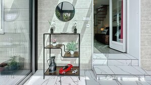 A modern interior with a glass door, a round mirror, and a metal shelf with decorative items. - Ty Ar Mor by Interhome (La Bernerie-en Retz)
