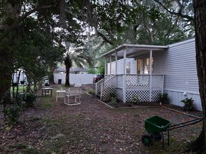 A covered porch with a lattice railing, a small table, and a chair.