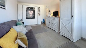 Una sala de estar moderna con un sofá gris, un póster grande y un armario blanco.