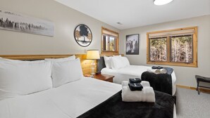 A hotel room with two beds, a nightstand with a lamp, and a window with a view of trees. - Beaver Lake Pond & Pines Cabin (Custer)