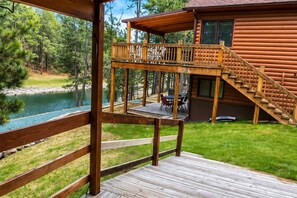 A wooden deck with a view of a lake and a cabin. - Beaver Lake Pond & Pines Cabin (Custer)