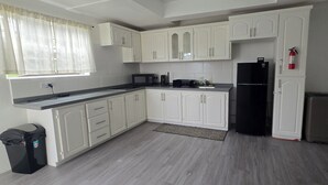Una cocina con armarios blancos, un refrigerador negro, un microondas y una cafetera.