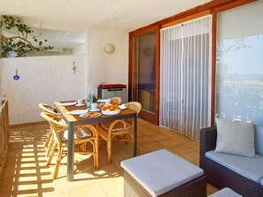 Un balcón con una mesa de comedor, sillas, un sofá y vistas al mar.