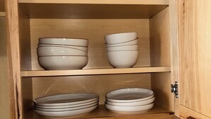 Un armario de madera con varios estantes, cada uno sosteniendo tazones y platos apilados.