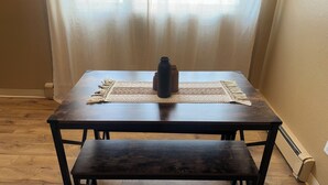 Una mesa de madera con acabado oscuro, un posavasos tejido y un jarrón oscuro.