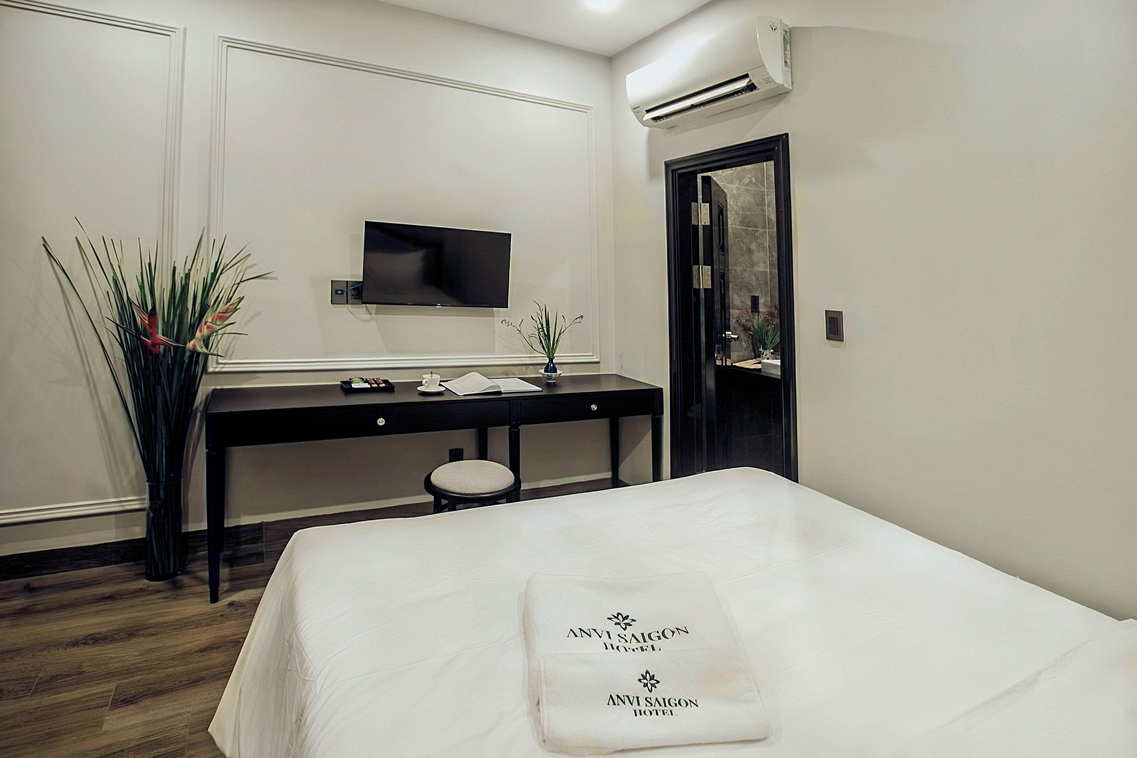 Een hotelkamer met een bed, bureau, televisie en spiegel.