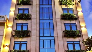 The exterior of the Anvi Saigon Hotel with illuminated signage, multiple balconies with plants, and a clear sky. - Anvi Saigon Boutique Hotel (Ho Chi Minh City)