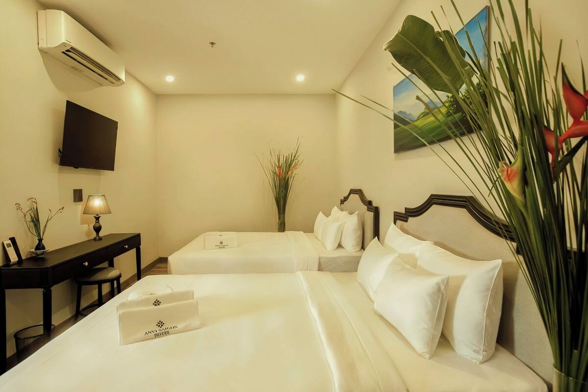 A hotel room with two beds, a desk, a TV, and a large window with a view.
