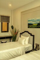 Une chambre d’hôtel avec deux lits, un bureau, un téléphone et un tableau au mur.