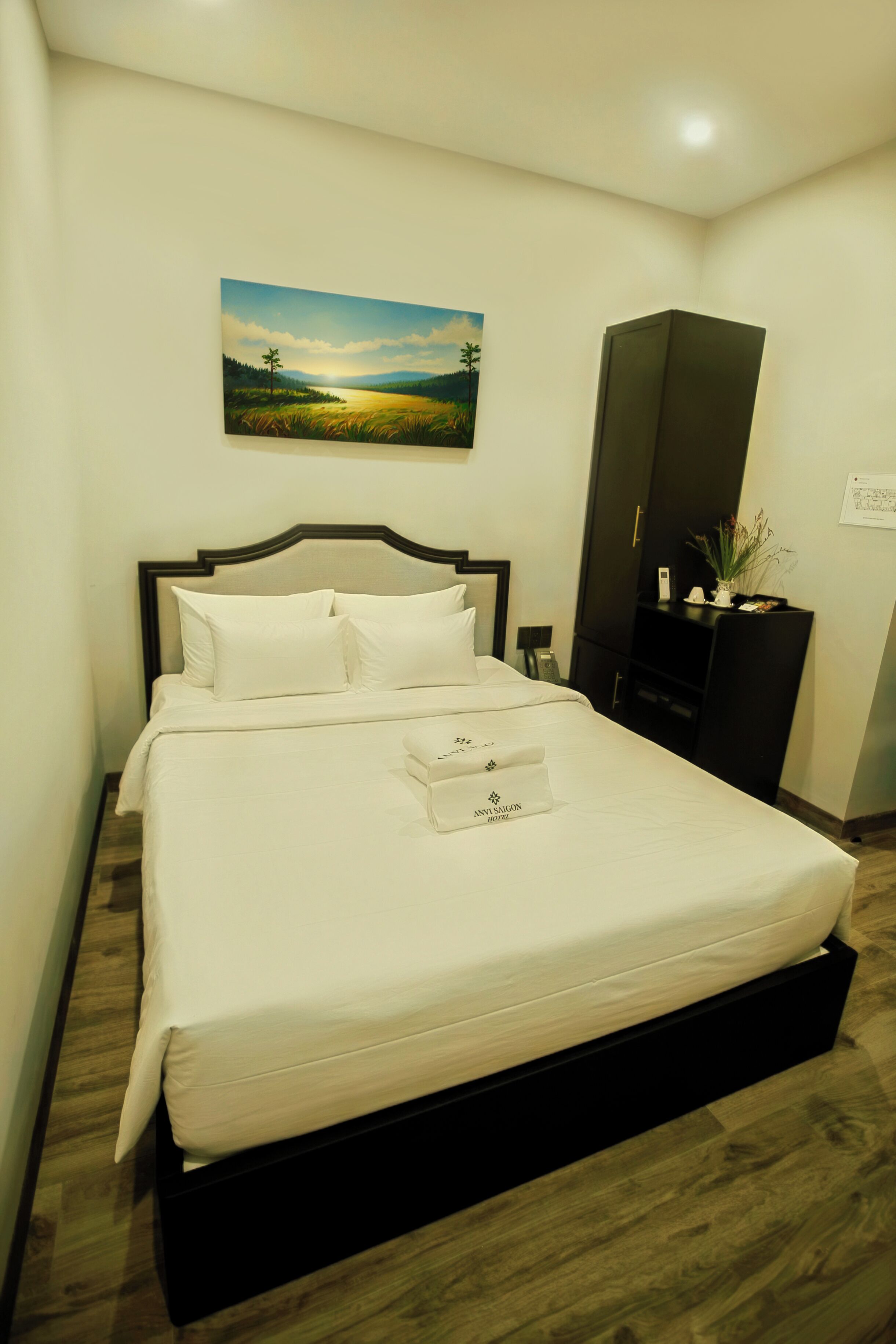 A neatly made bed with white linens, a headboard, and a bedside table with a lamp.