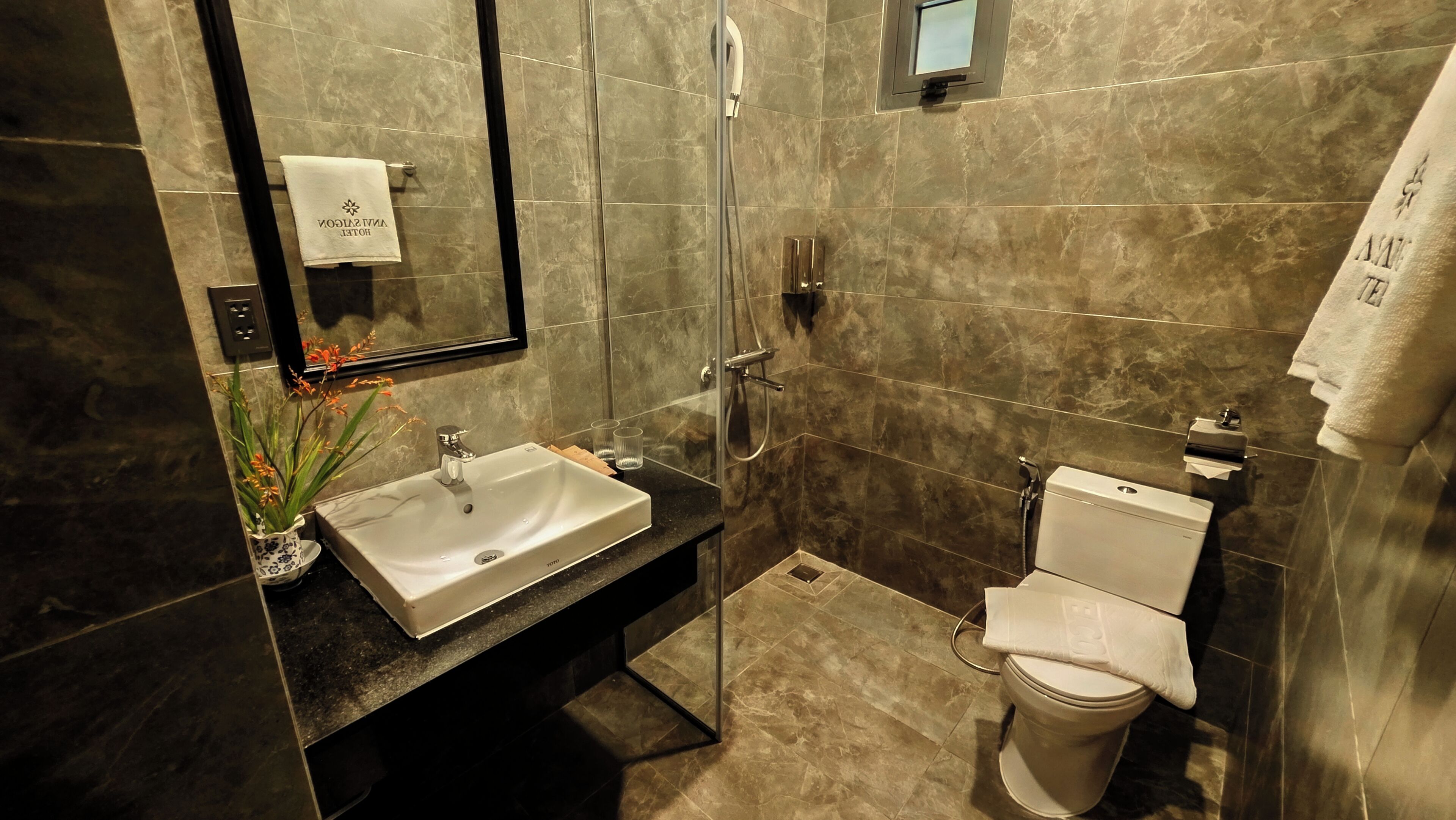 Un baño moderno con lavamanos, espejo, ducha y retrete.