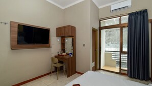 Habitación de hotel con cama, escritorio, silla, televisor y balcón con cortinas.