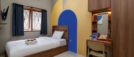 Una habitación de hotel con cama, escritorio, silla y ventana con cortinas.