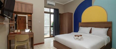 A hotel room with a bed, a desk with a chair, a television, and a window with curtains.