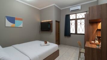 Une chambre d’hôtel avec un lit, un bureau, une télévision et une fenêtre avec des rideaux.