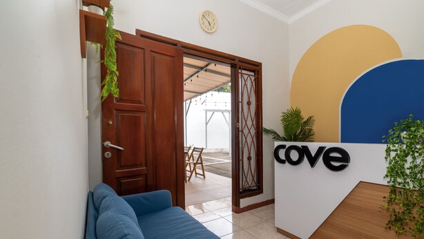 Un área de recepción con una puerta de madera, un sofá azul, un reloj y un letrero que dice 'cove'.