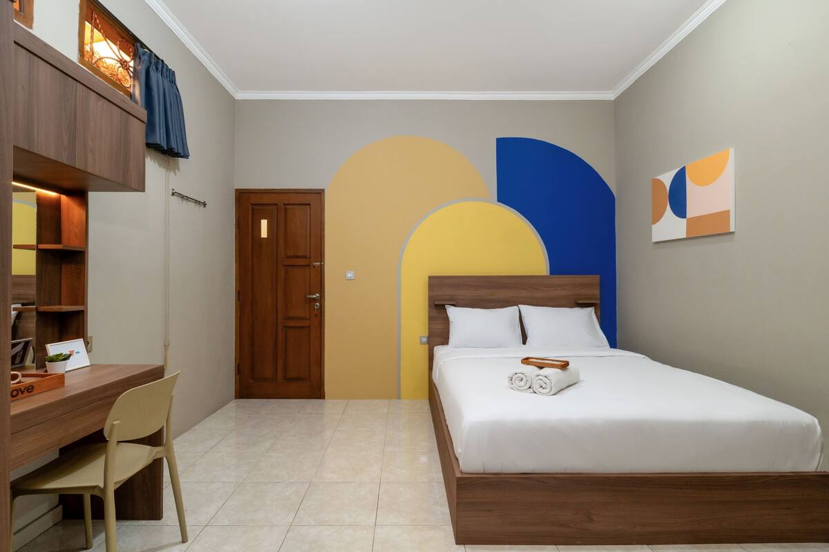 A bedroom with a bed, a desk, a chair, and a door.