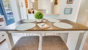 Un comedor con una mesa de madera, cuatro sillas, una planta en maceta y una revista.