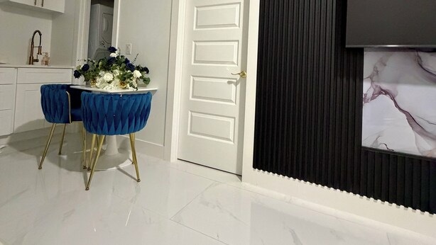 Una cocina moderna con armarios blancos, una mesa de comedor tapizada en azul y un jarrón decorativo.